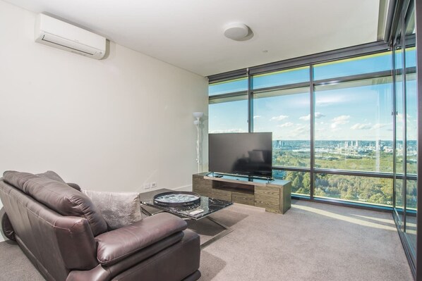 Una sala de estar moderna con un sofá de cuero, un televisor de pantalla plana y un ventanal con vistas a la ciudad.