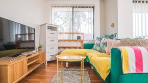A cozy living room with a television, a wooden desk, a green sofa, and a white cabinet. - Simple Comfort! 2bed1bath Unit in Meadowbank (Meadowbank)