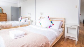 A clean, minimalist bedroom with two beds, white bedding, and a mirror reflecting the room. - Simple Comfort! 2bed1bath Unit in Meadowbank (Meadowbank)