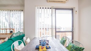 A modern living room with a wooden dining table, green sofa, and white chairs. - Simple Comfort! 2bed1bath Unit in Meadowbank (Meadowbank)