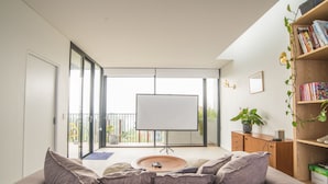 A modern living room with a large sofa, a coffee table, a bookshelf, and a blank TV screen. - Inner City Penthouse With Private Rooftop (Waterloo)