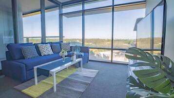 Un salón moderno con un sofá azul, una mesa de centro y un amplio ventanal con vistas al paisaje.