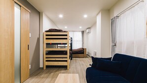 Une petite pièce comprenant un lit superposé, un canapé, une table en bois et une armoire.