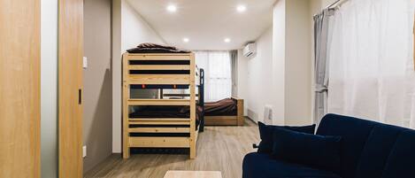 Habitación compacta con una cama nido, un sofá, una mesa de madera y un armario.