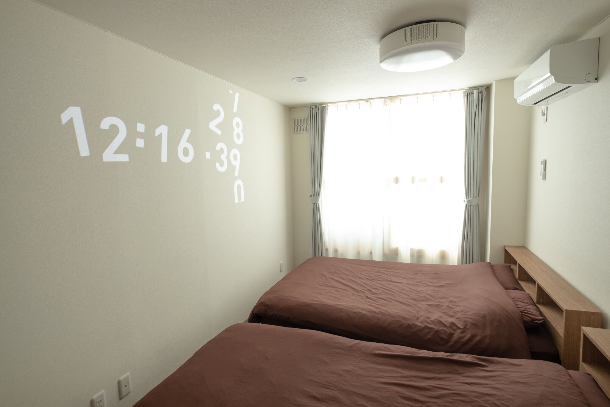 Ein Hotelzimmer mit zwei Betten, einer Wanduhr und einer Klimaanlage.