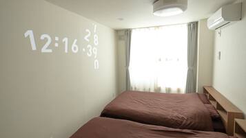 Een hotelkamer met twee bedden, een wandklok en een airconditioning.