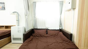 A bedroom with a bed, a heater, and a window with curtains.