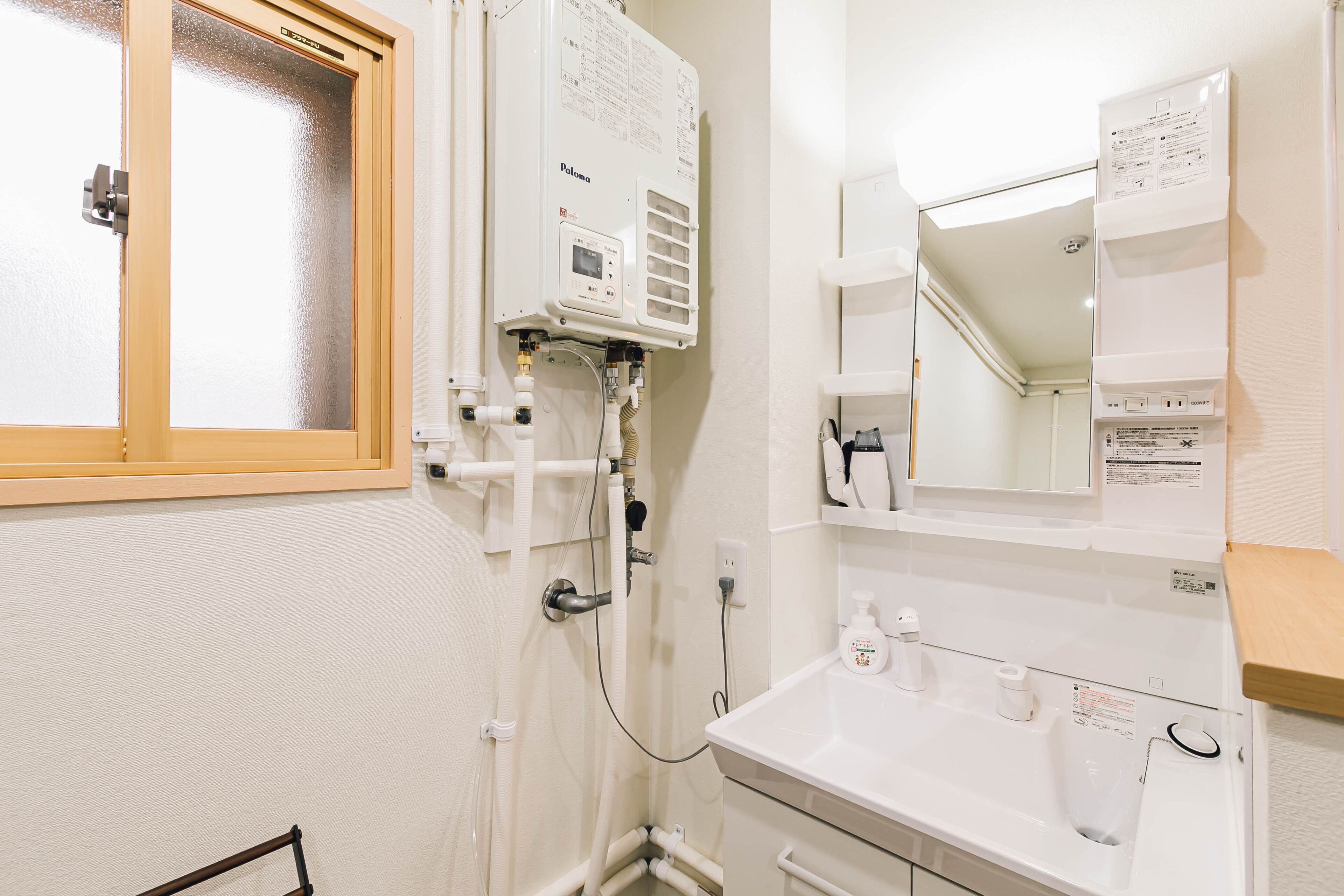 Une salle de bain avec un lavabo blanc, un miroir et une fenêtre.