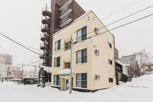 A multi-story building with a snow-covered ground, a visible entrance, and several windows.