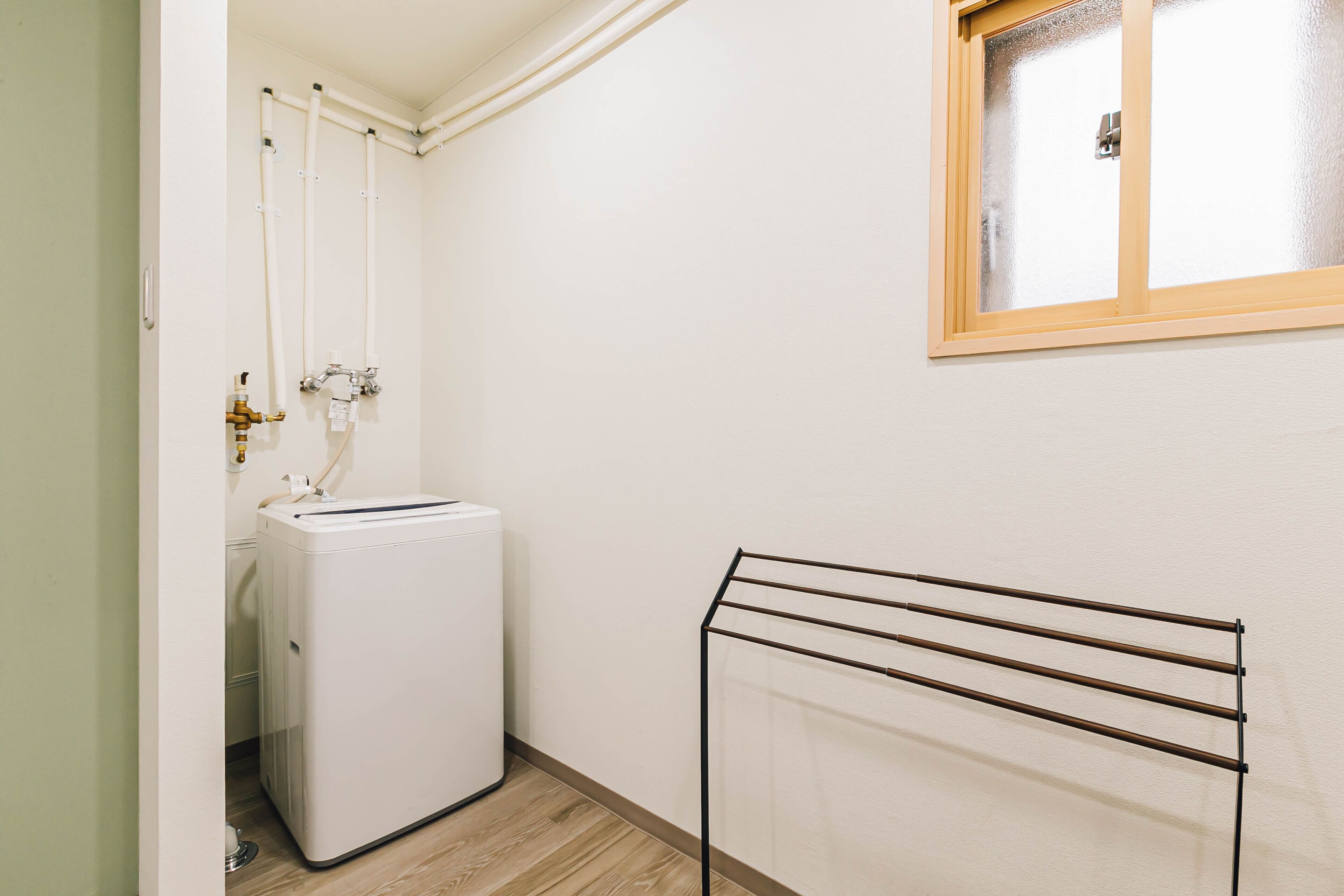 Un espace dédié à la lessive, comprenant un lave-linge, un étendoir et une fenêtre avec un cadre en bois.