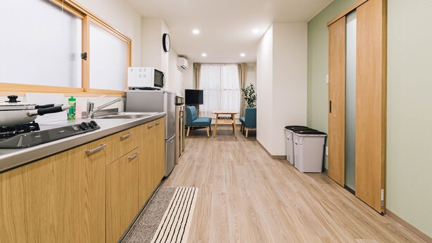 Une cuisine moderne avec des meubles en bois, un four à micro-ondes, une cuisinière et un évier. Il y a un petit coin repas avec une table et des chaises.
