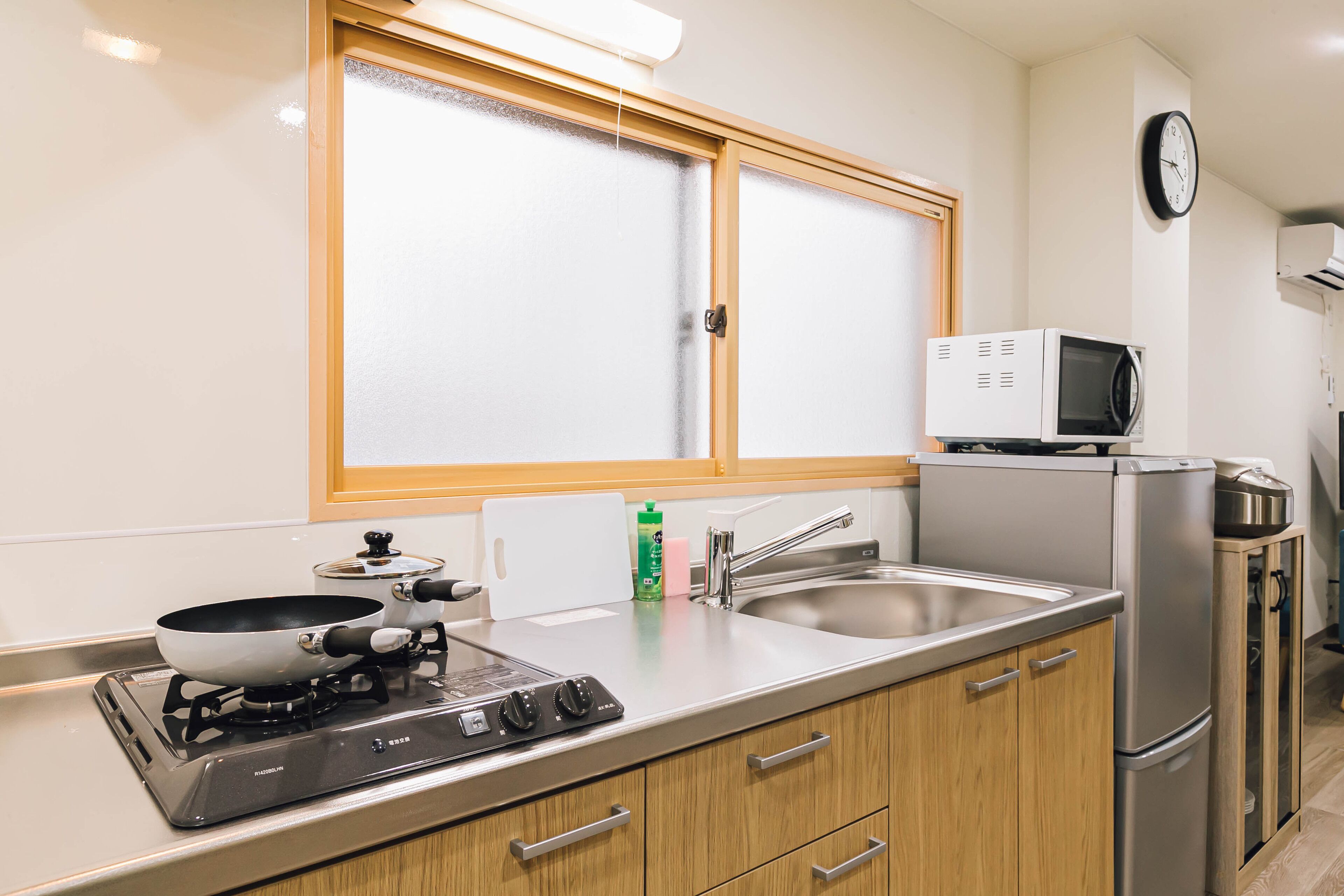 A modern kitchen with a gas stove, microwave, refrigerator, and stainless steel sink.