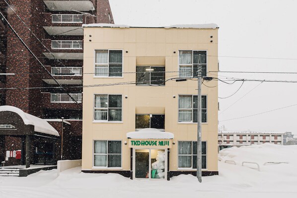 Un edificio de varios pisos con una entrada cubierta de nieve y un letrero que dice "TKD HOUSE".