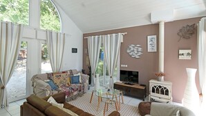 Un salón amplio con un ventanal grande, chimenea y televisor.