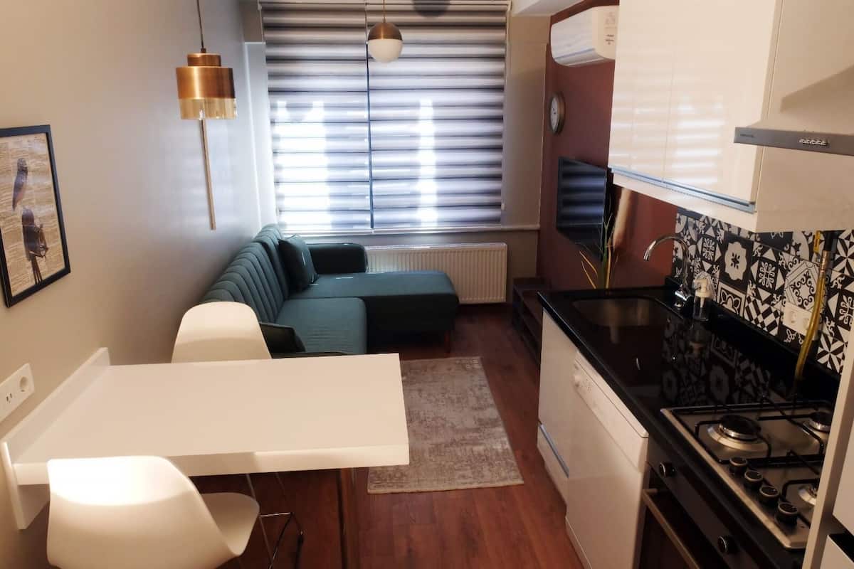 A compact kitchen with a stove, sink, and a dining area with a table and chairs.