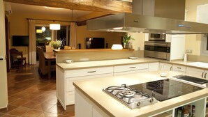 Una cocina moderna con una isla central, horno empotrado y campana extractora de acero inoxidable.