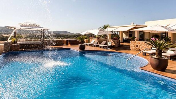 Una piscina con fuente, sillas de descanso y plantas en macetas.