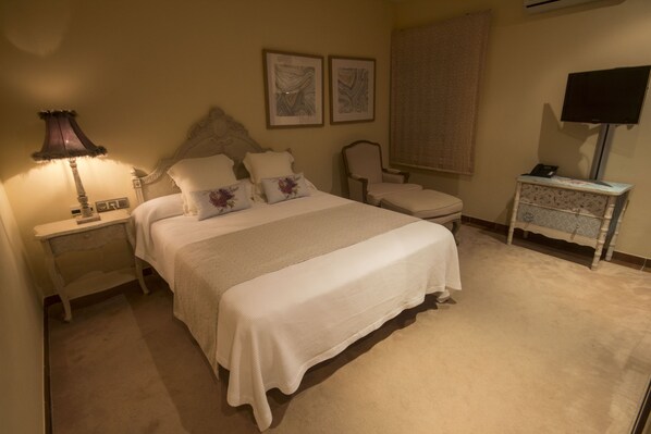 Un dormitorio ordenado con cama, mesitas de noche, una silla y un mueble para televisor.