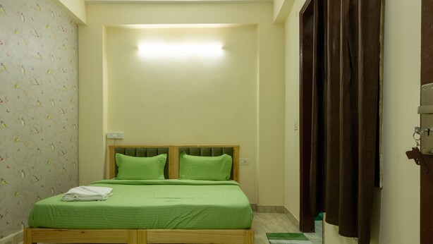 Une chambre à coucher avec un lit en bois, une literie verte, un tapis vert et un rideau.