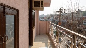 Un balcon donnant sur un quartier résidentiel, une porte et un appareil de climatisation.