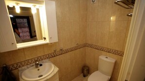 Ein Badezimmer mit Waschbecken, Spiegel, Toilette und Mülleimer.