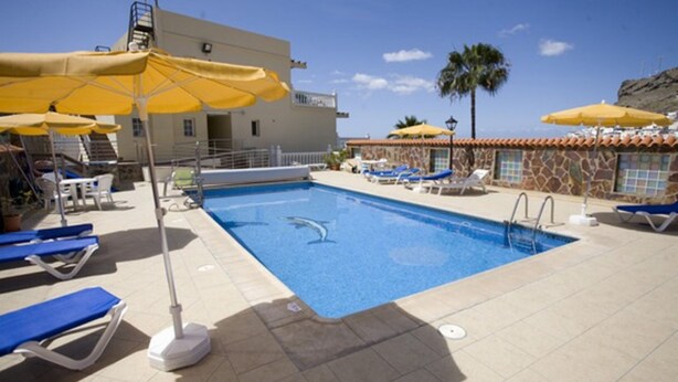 Ein Swimmingpool mit blauem Wasser, umgeben von Liegestühlen und gelben Sonnenschirmen.