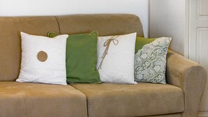 Ein beiges Sofa mit drei Kissen in verschiedenen Mustern und Farben.