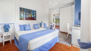 Ein Schlafzimmer mit einem großen Bett, einem Gemälde darüber, einem Schreibtisch mit Stuhl und einem Kleiderschrank.