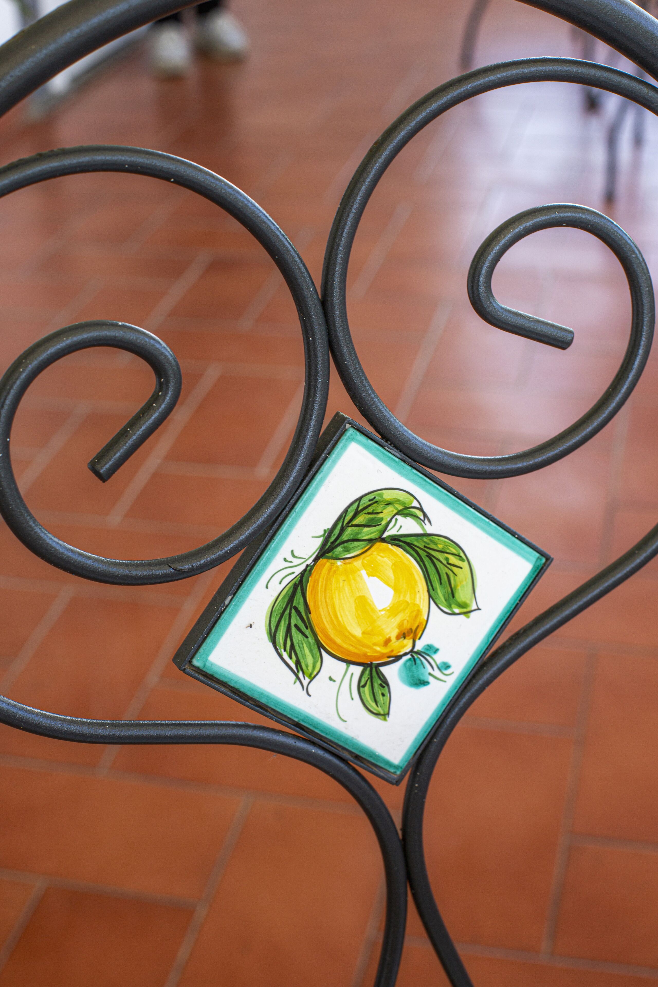A metal table with a decorative tile featuring a lemon.