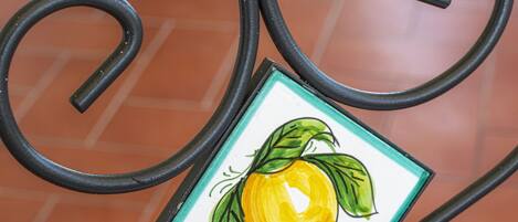 A metal table with a decorative tile featuring a lemon.