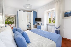 A bedroom with a bed, a desk, a television, and a window with curtains. - Villa Maresca B&B (Piano di Sorrento)