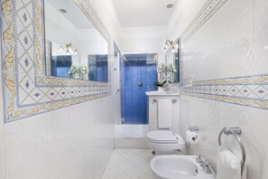 A bathroom with a blue shower enclosure, a toilet, a bidet, and a sink with a towel rack. - Villa Maresca B&B (Piano di Sorrento)