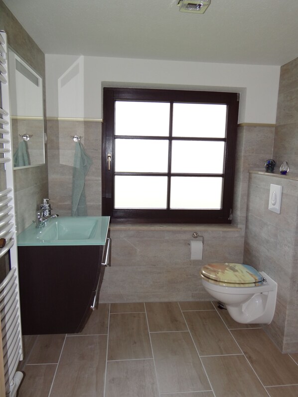 A bathroom with a large window, a sink, a toilet, and a mirror. - Urlaub mit dem Haustier im Wald (Rostock-Wiethagen)