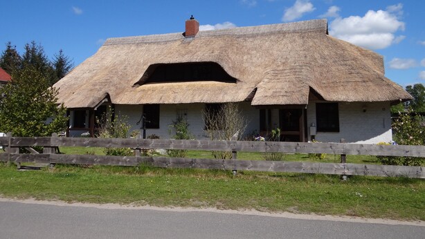 A traditional thatched-roof house with a wooden fence in front. - Urlaub mit dem Haustier im Wald (Rostock-Wiethagen)