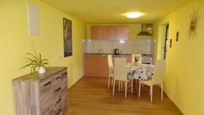 A compact kitchen with wooden cabinets, a dining table with chairs, and a potted plant. - Urlaub mit dem Haustier im Wald (Rostock-Wiethagen)