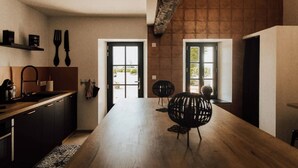 Une cuisine moderne avec un plan de travail en bois, des armoires noires et une grande table à manger accompagnée d’une chaise noire.