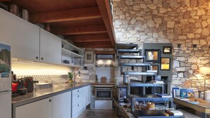 A modern kitchen with stone walls, wooden beams, and stainless steel appliances. - Live in the Acropolis' Shadow-now w/ super Terrace
 (Athina)