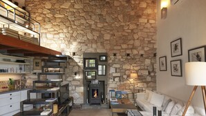 A cozy living room with a stone wall, a fireplace, a sofa, and a coffee table. - Live in the Acropolis' Shadow-now w/ super Terrace
 (Athina)