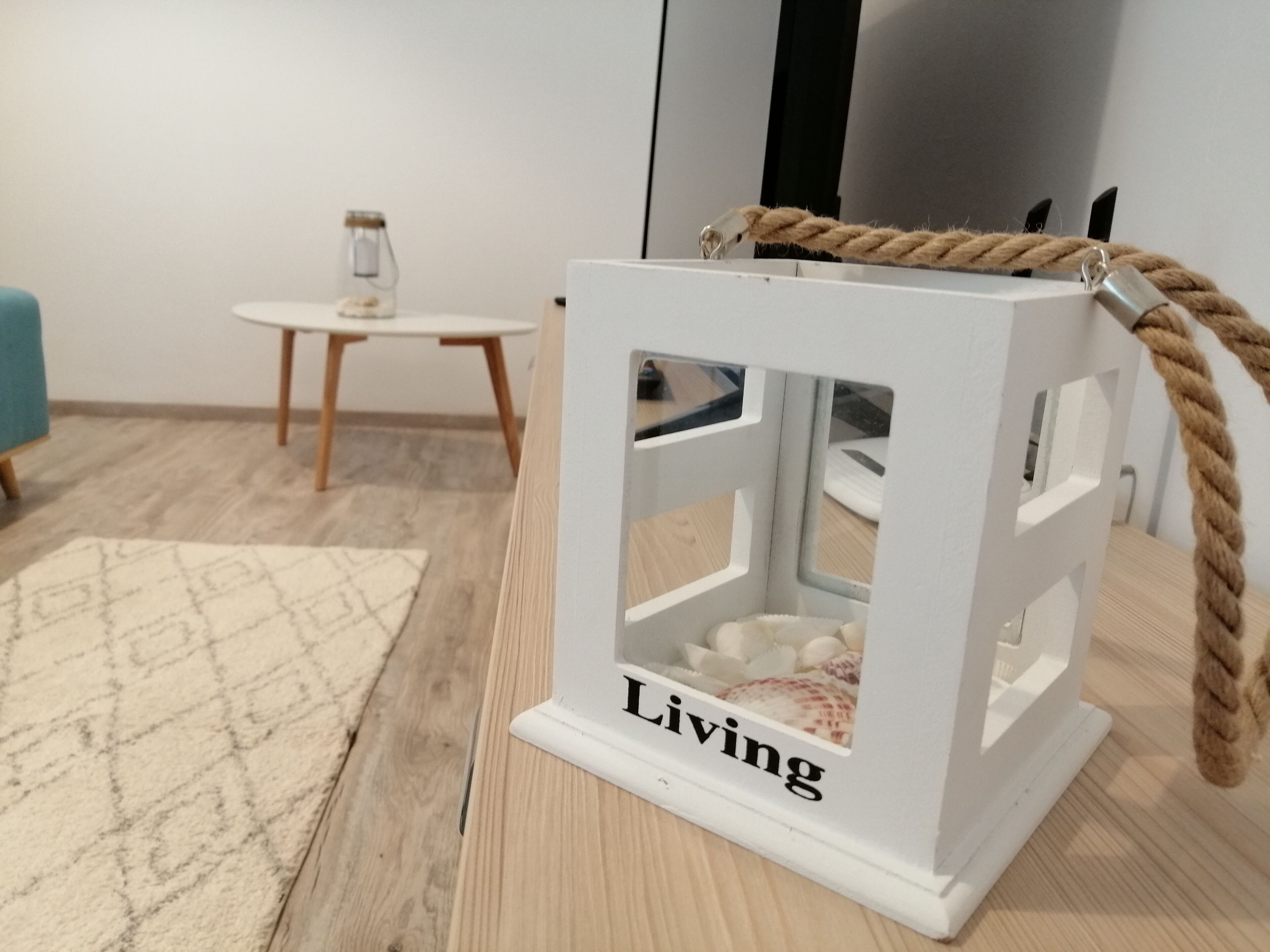 A white lantern with the word "Living" on a wooden table.