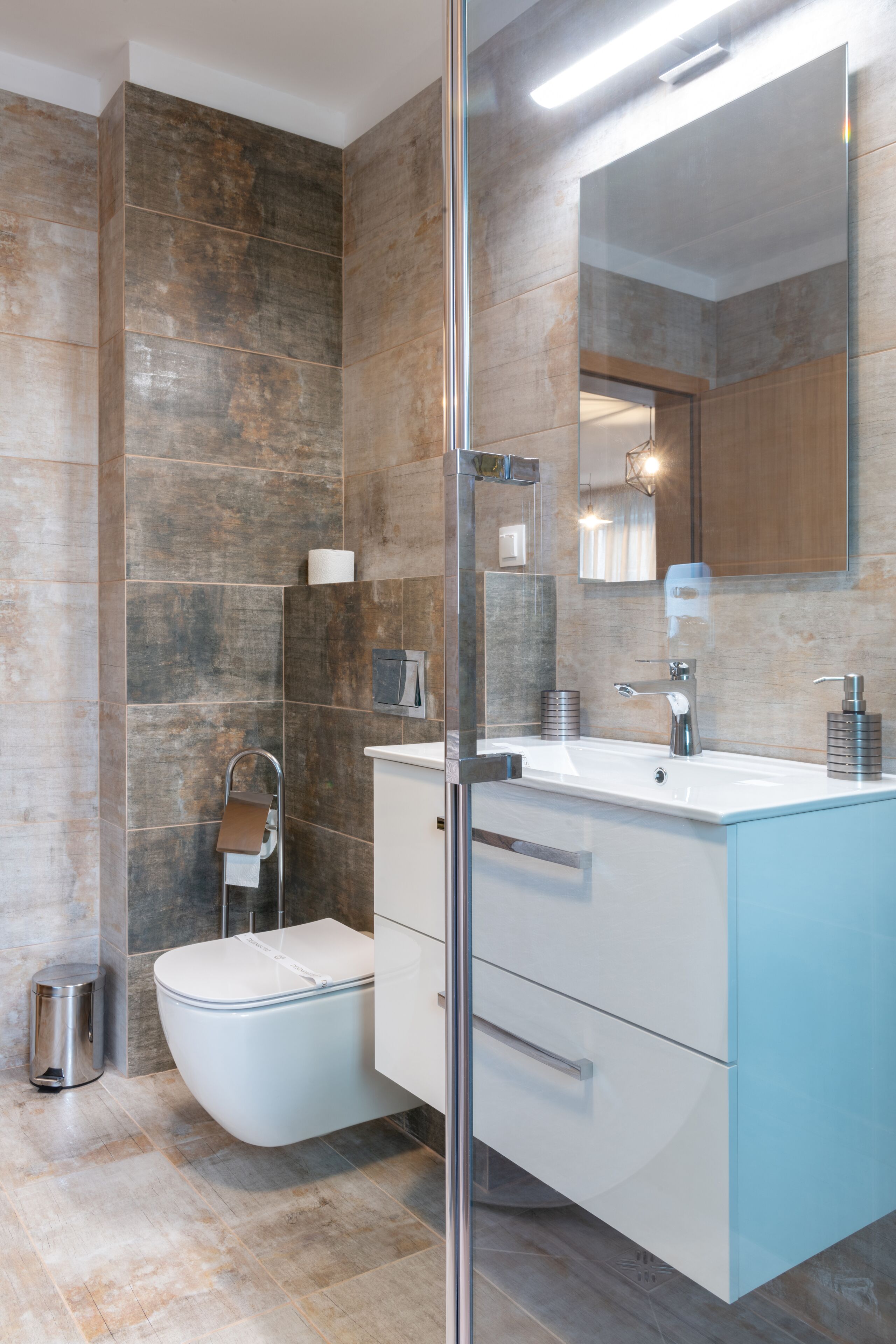 A modern bathroom with a glass shower enclosure, a white toilet, and a vanity with a mirror.