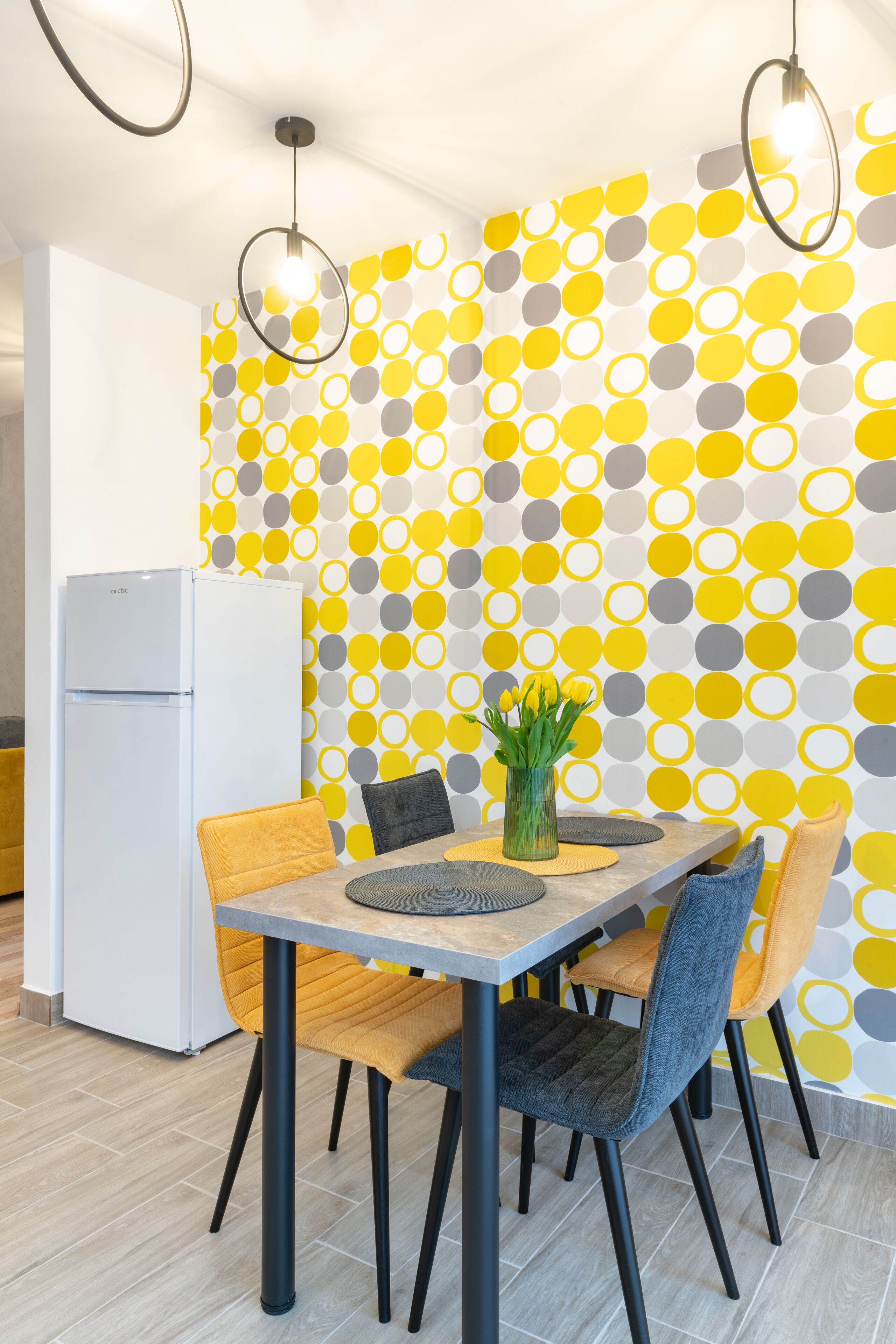 Un comedor con una mesa, sillas y una pared con un diseño circular.
