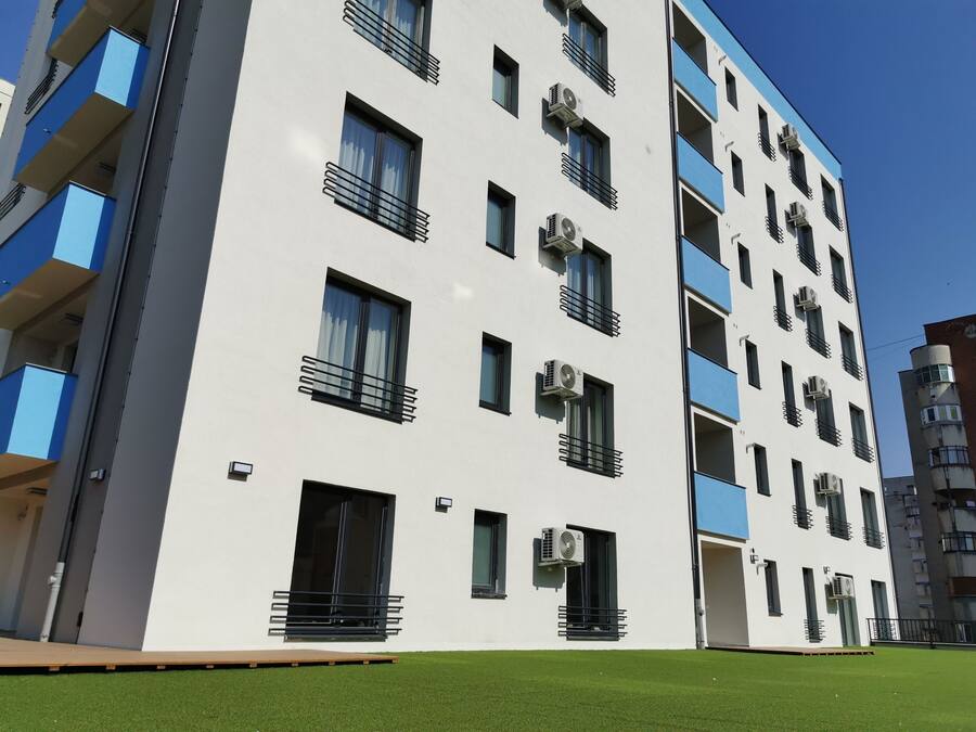 A multi-story residential building with balconies, air conditioning units, and a flat roof.