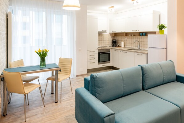 A modern kitchen with white cabinets, a built-in oven, and a coffee maker. - TCI Apartments (Cluj-Napoca)