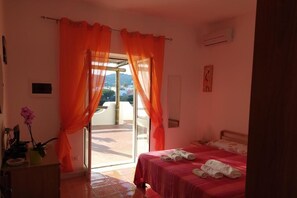 Un dormitorio con cama, un escritorio con una planta y vistas al exterior.