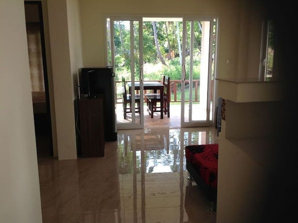 A spacious living area with a sliding glass door leading to a patio, a television, and a red sofa.