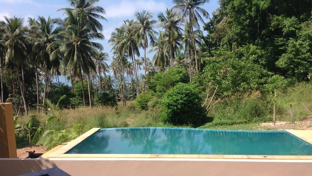 Une piscine rectangulaire à l’eau d’un bleu limpide, entourée d’une terrasse de couleur beige.