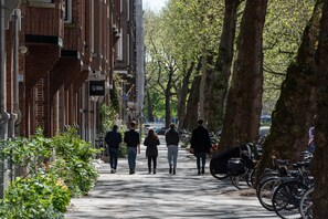 A tree-lined urban street with pedestrians and parked bicycles. - Le Petit Marin Boutique Hotel (Rotterdam)