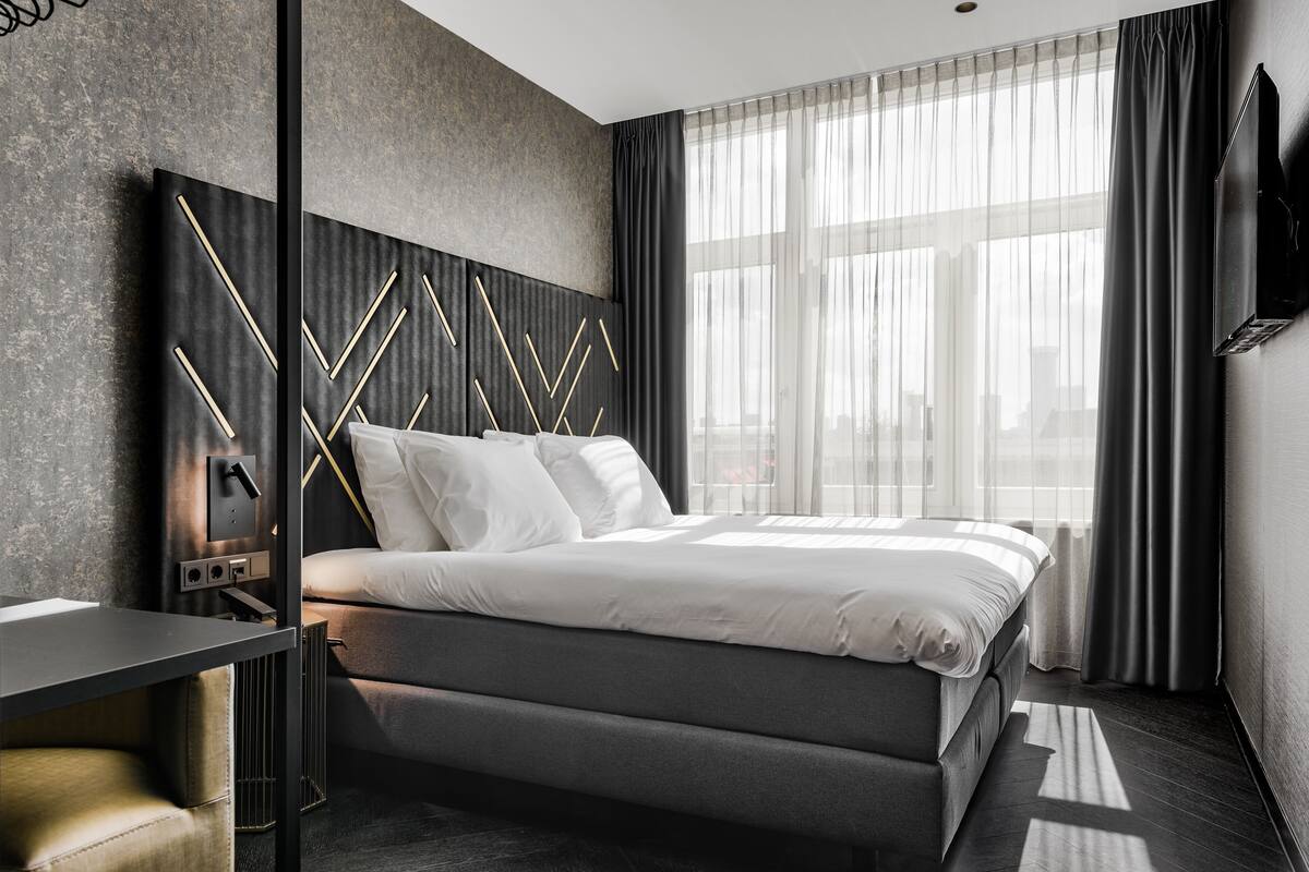 Une chambre moderne avec un grand lit, une table de chevet et un téléviseur fixé au mur.
