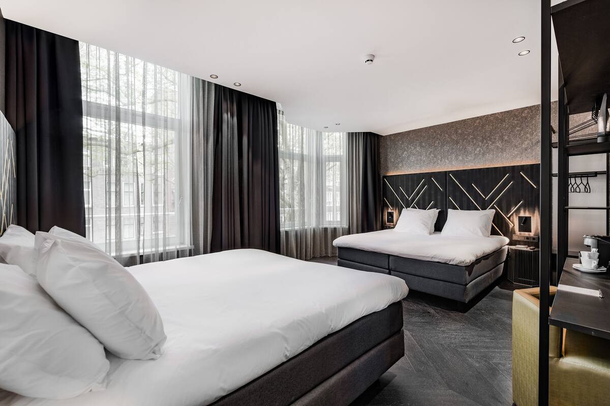 Une chambre d’hôtel moderne équipée d’un grand lit, d’un lit plus petit et d’un bureau avec une chaise.