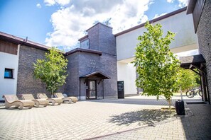 Zona de recepció d'hotel amb façana de pedra, un rètol sobre l'entrada i filera de butaques a l'exterior.